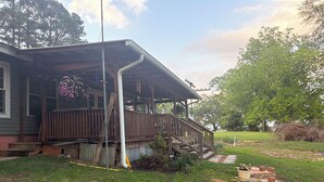 Een huis met een veranda, een houten trap en een gazon.