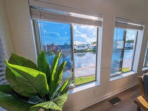 A room with large windows, a potted plant, and a view of a water body and buildings. - 4BR, 5 min ride to Ocean|Golf cart|Pool|Waterfront (Myrtle Beach)