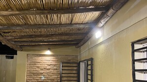 Een overdekte buitenruimte met een bamboe plafond, een stenen muur en een metalen poort.