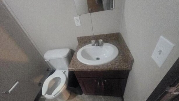 Ein kleines Badezimmer mit Toilette, Waschbecken und Spiegel.