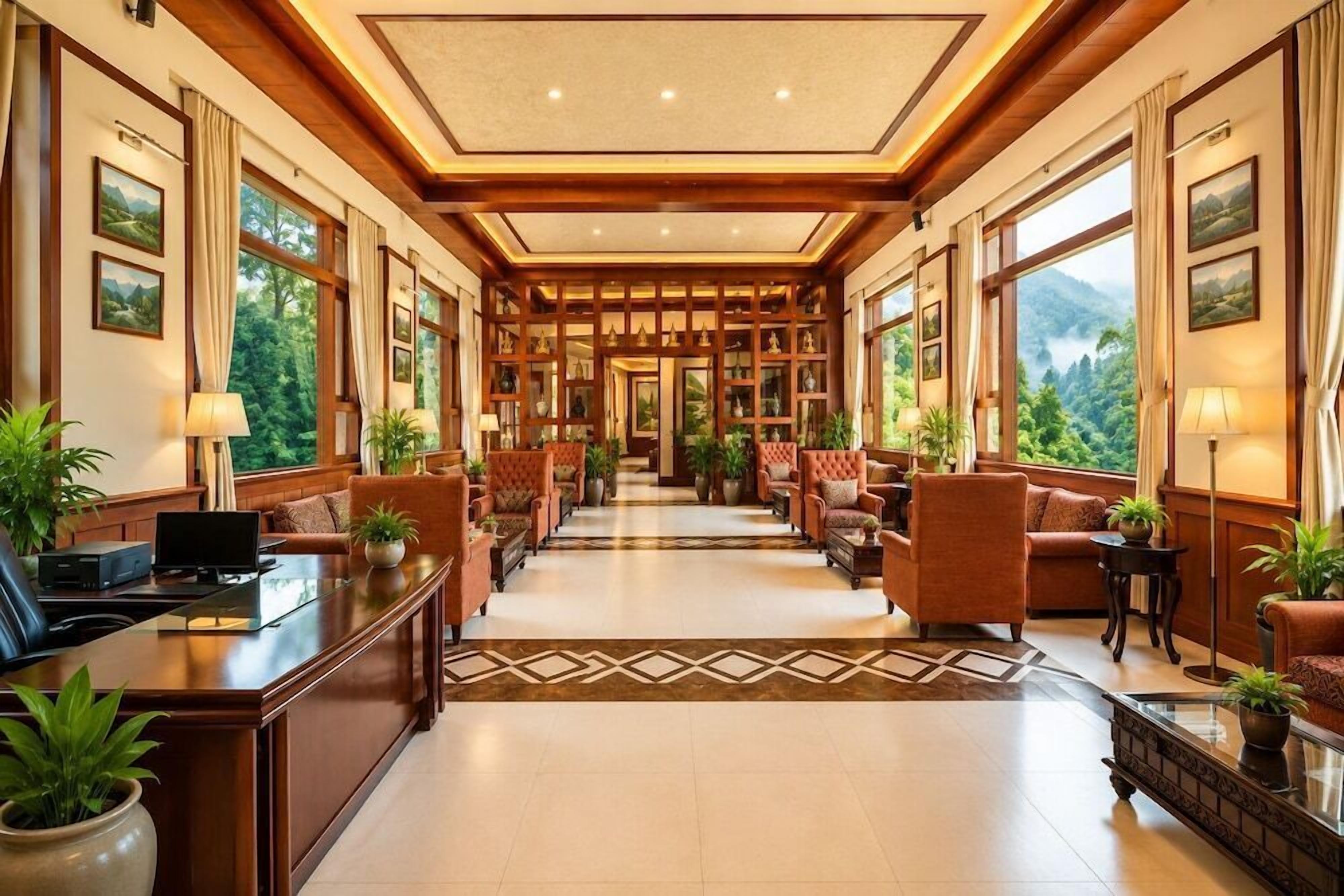 Un vestíbulo de hotel con una recepción, zona de estar y amplios ventanales con vistas al exterior.
