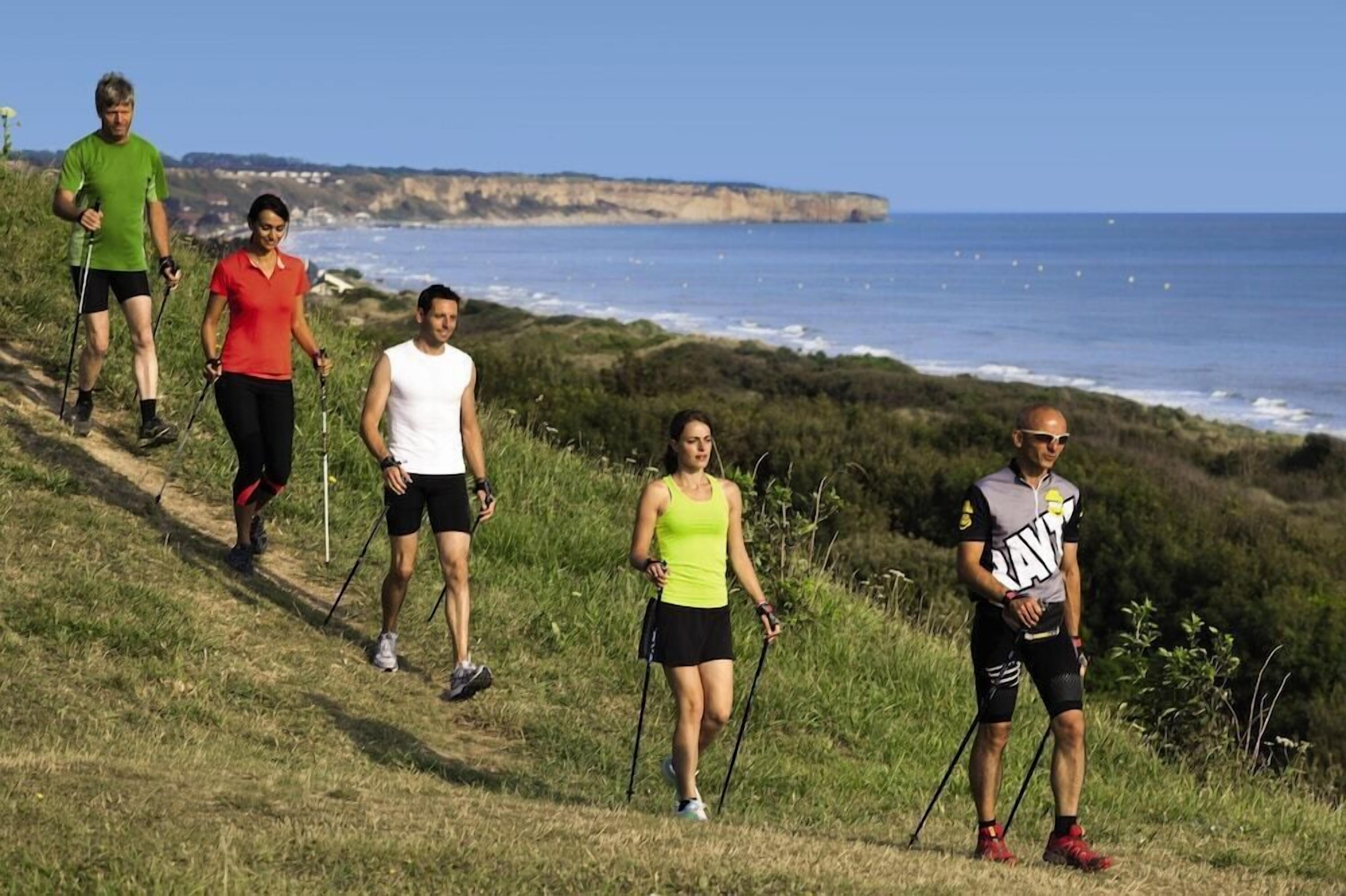 A group of people hiking on a coastal path with cliffs in the background.