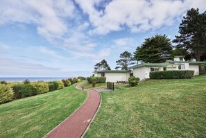 A pathway leading to a building with a green roof, surrounded by well-maintained grass and trees. - Belambra Colleville Sur Mer Omaha Beach (Colleville-sur-Mer)