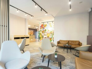 Un interior moderno con zonas de estar, una recepción y un mural colorido.