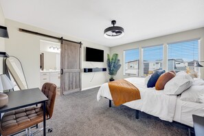 A hotel room with a bed, desk, chair, TV, and a sliding door leading to a bathroom.