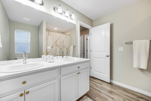 A bathroom with two sinks, a mirror, and a shower curtain. - The Hills in Lorson Ranch (Colorado Springs)
