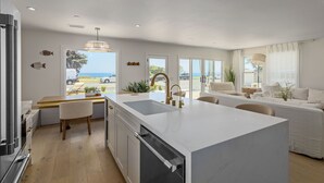 Una cocina moderna con una isla grande, comedor y vista al mar.