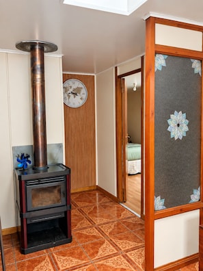 A room with a wood-burning stove, a world map clock, and a traditional Japanese shoji screen.
