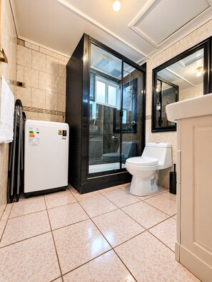 A modern bathroom with a glass-enclosed shower, a toilet, and a water heater.