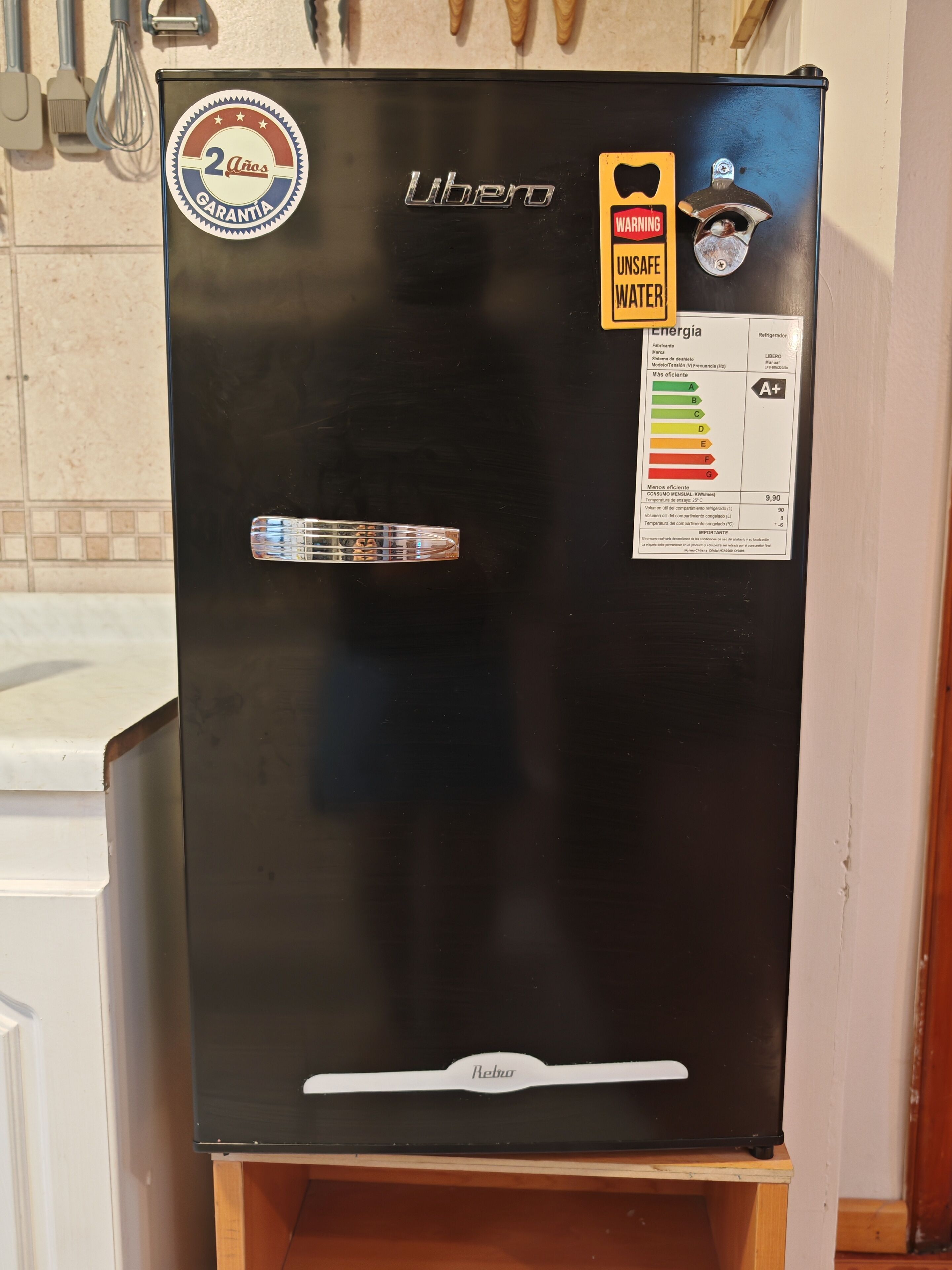 Ein schwarzer Kühlschrank mit 'Libero'-Logo, einem '2 Años Garantia'-Aufkleber, einem Warnhinweis wegen 'UNSICHERES WASSER' und dem Markennamen 'Rebhu'.