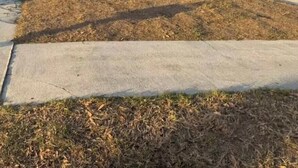 Una propiedad residencial con garaje, porche cubierto y césped.