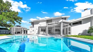 Ein modernes Haus mit Swimmingpool, großen Fenstern und blauem Himmel.