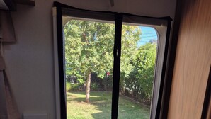 A kitchen area with a sink, countertop, and a window with a view of a grassy yard and trees. - Quirky & Comfortable: A 'Tiny Home' Experience in a great spot (Heidelberg)