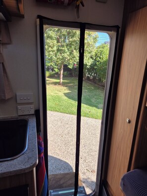 A kitchen area with a sink, countertop, and a window with a view of a grassy yard and trees.