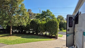 A gravel driveway leading to a white RV parked on a residential street. - Quirky & Comfortable: A 'Tiny Home' Experience in a great spot (Heidelberg)