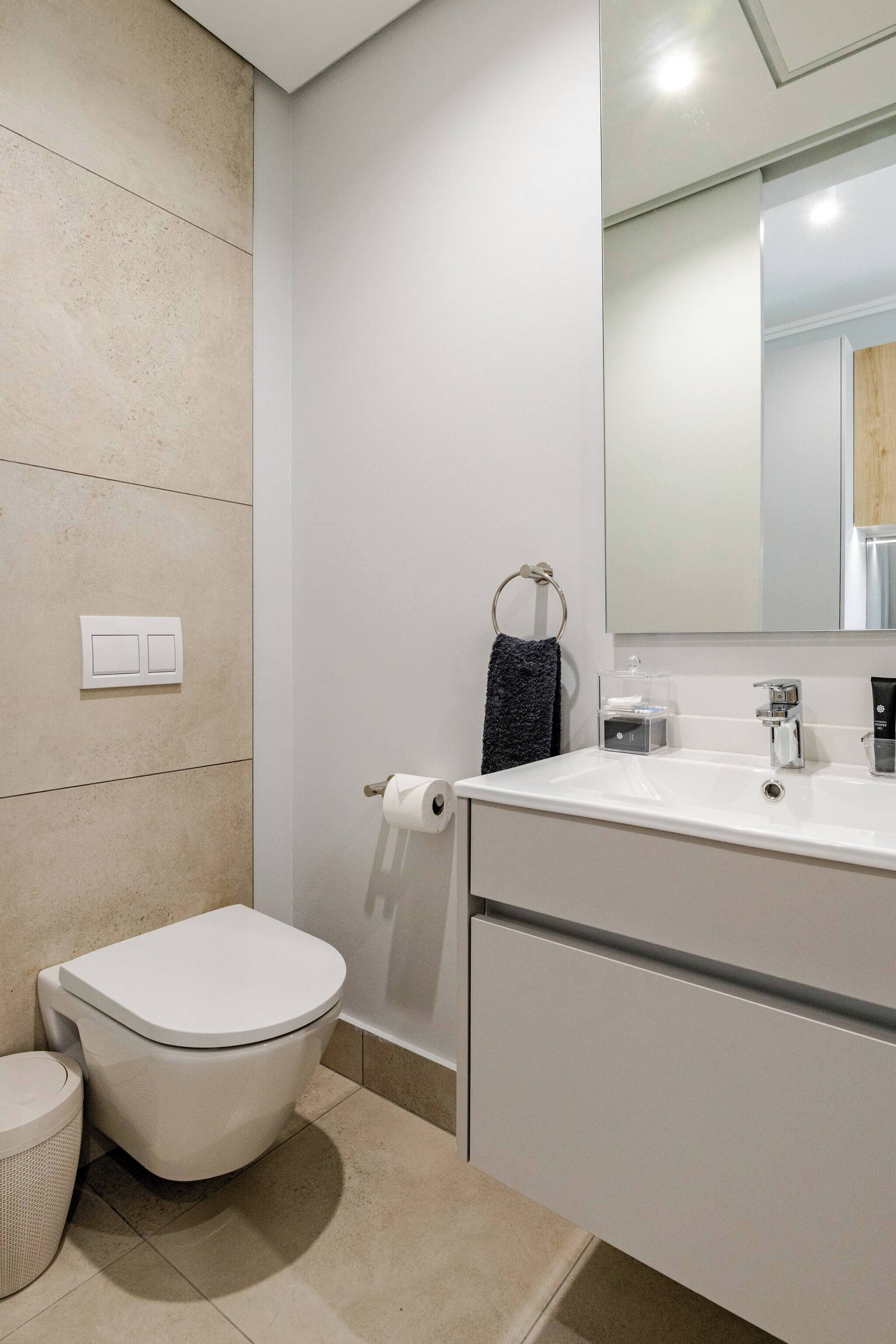 Une salle de bain moderne avec des toilettes, un lavabo et un miroir.