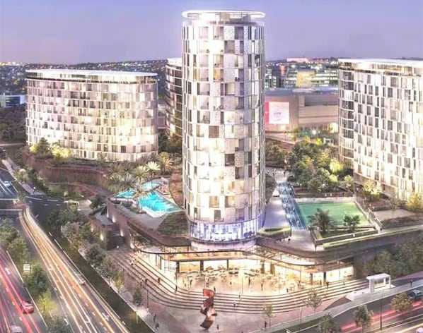 A modern hotel with a central tower, multiple floors, and a pool area.
