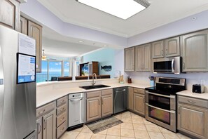 Una cocina moderna con electrodomésticos de acero inoxidable, armarios de madera y vistas al exterior.