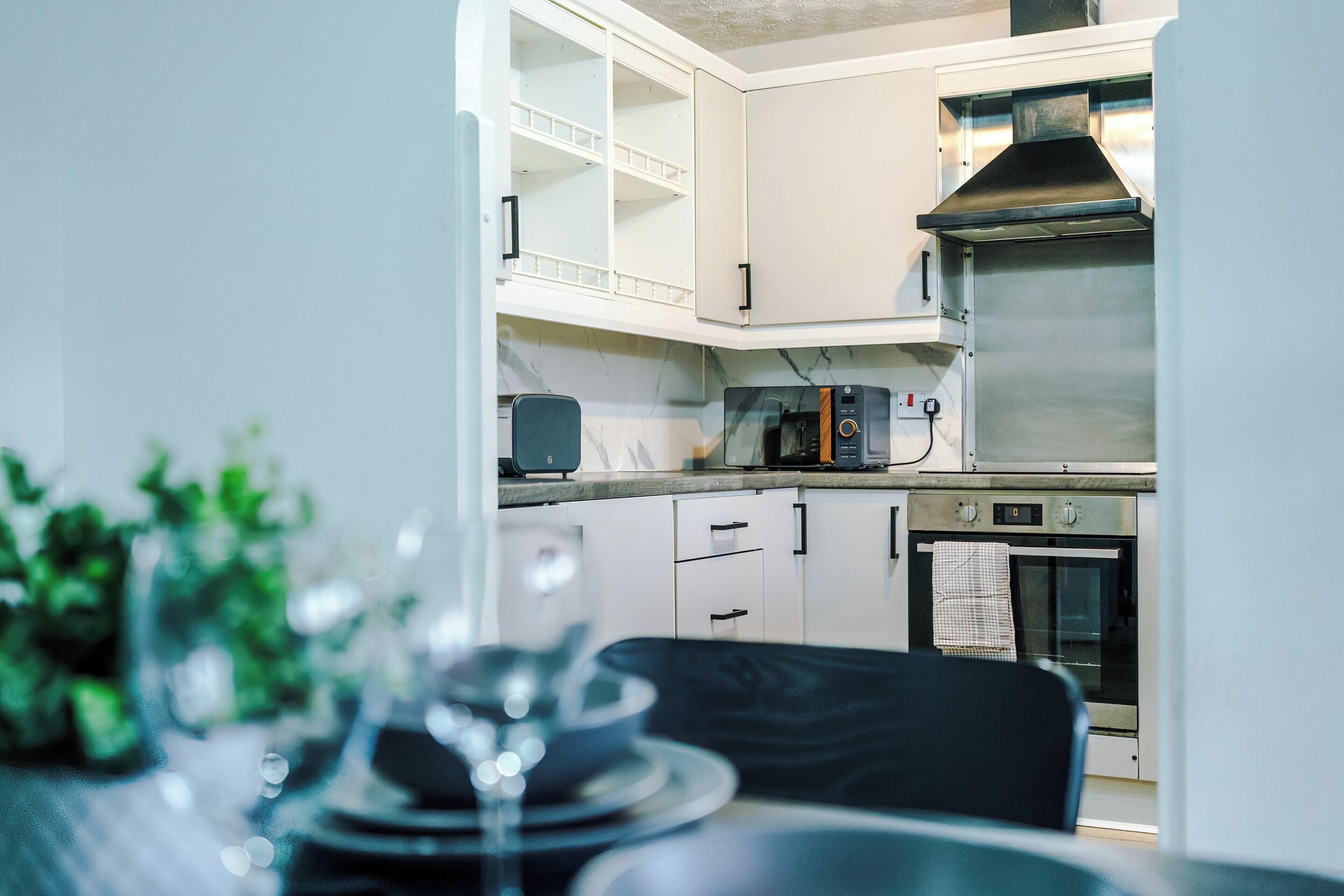 A modern kitchen with white cabinets, a built-in oven, and a microwave.