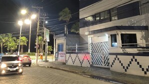 A nighttime urban street with buildings, streetlights, and parked cars. - Beachfront apartment in Praia Grande, right on the sand. (Praia Grande)