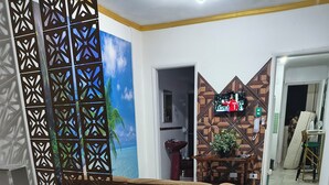 A room with a sofa, a TV, a decorative wall, and a view of the sea. - Beachfront apartment in Praia Grande, right on the sand. (Praia Grande)
