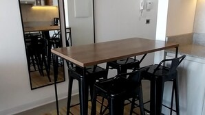 A dining area with a wooden table and black chairs, a mirror, and a hanging light fixture.