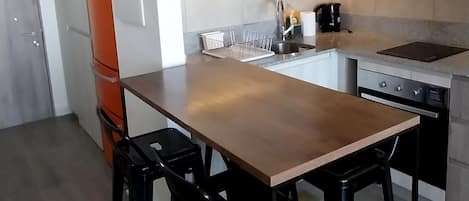 A modern kitchen with a wooden table, black chairs, and a striped rug.