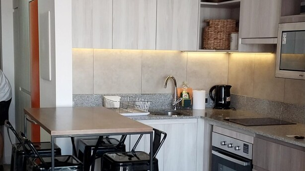 A modern kitchen with a central island, built-in appliances, and a dining area with chairs.