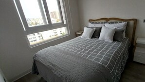 A bedroom with a bed, a window, a nightstand, and a dresser.