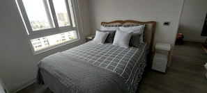 A bedroom with a bed, a window, a nightstand, and a dresser.
