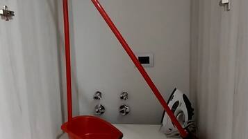 A white cabinet with a red broom and dustpan inside.