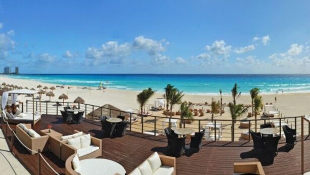 Eine Terrasse mit Sitzgelegenheiten, mit Blick auf Strand und Meer.