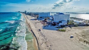 Ein Hotel an der Küste mit Blick auf den Strand, einem Pool und einem großen Gebäude mit blauem Dach.