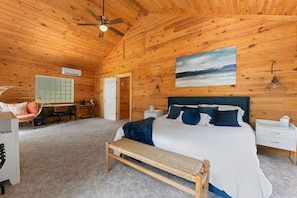 A wooden-paneled bedroom with a bed, a desk, a chair, and a ceiling fan. - Lakefront Retreat on High Rock Lake - Dock, Kayaks & Game Room (Denton)