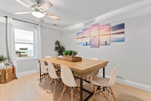 A dining area with a wooden table, six chairs, a ceiling fan, and a view of the outdoors through a window. - Lakefront Retreat on High Rock Lake - Dock, Kayaks & Game Room (Denton)