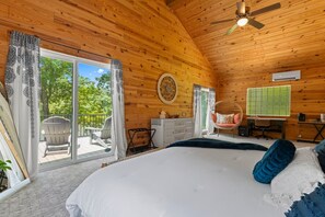 A wooden cabin bedroom with a bed, a desk, a chair, and a view of the outdoors. - Lakefront Retreat on High Rock Lake - Dock, Kayaks & Game Room (Denton)
