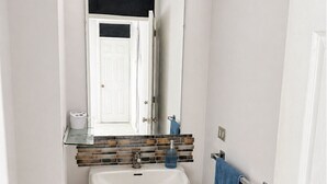 Un baño con tocador blanco, un espejo con luces, un lavabo y un perchero para toallas.
