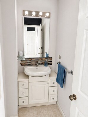A bathroom with a white vanity, a mirror with lights, a sink, and a towel rack. - Suite in Zone 10 : Exclusive and secure location (Ciudad de Guatemala)