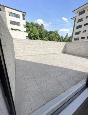 A courtyard with tiled flooring, a stone wall, and modern buildings in the background. - Suite in Zone 10 : Exclusive and secure location (Ciudad de Guatemala)