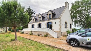 Ein zweigeschossiges Haus mit einer Stein-Fassade, einer Veranda und einem Auto auf der Einfahrt.