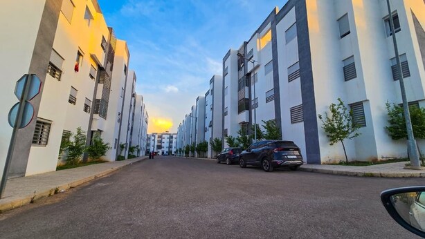 A street lined with modern buildings, parked cars, and a clear sky. - Elite Holiday Homes - Akdital & Aéroport (Fes)