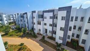 A modern residential building with multiple balconies, a paved driveway, and a small garden area. - Elite Holiday Homes - Akdital & Aéroport (Fes)