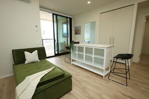 Ein modernes Wohnzimmer mit einem grünen Sofa, einem weißen Schrank und einem schwarzen Hocker.