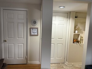 A hallway with a white door, a framed inspirational quote, a decorative mirror, and a shelf with decorative items. - Lovely 3-bedroom apartment with AC in Syracuse (Syracuse)