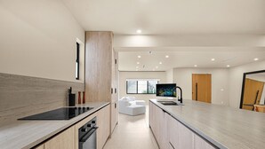 Una cocina moderna con una isla central, horno empotrado y un amplio ventanal.