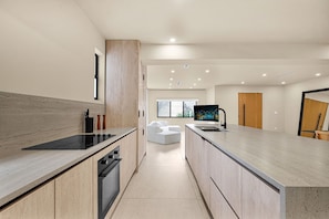 A modern kitchen with a central island, built-in oven, and a large window.