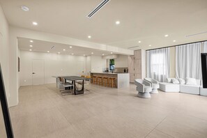 A spacious living area with a dining table, bar stools, a sofa, and a kitchen area with a bar.