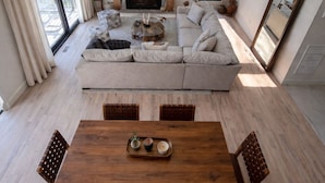 Una sala de estar moderna con chimenea, un televisor de pantalla plana grande, un sofá y una mesa de comedor con sillas.