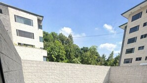 Um pátio com piso de azulejos, parede de pedra e edifícios modernos ao fundo.