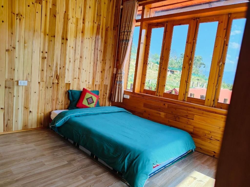 Una habitación con paneles de madera, una cama, un ventanal y vistas a follaje.